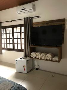 a room with a flat screen tv and towels at Pousada Armação das Baleias in Penha