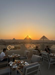 a group of people sitting at tables in a restaurant with the sunset at Boutique De Pirámides Nómadas in Cairo