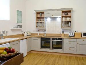 a kitchen with white cabinets and a bowl of fruit at Whitehall Pele Tower in Mealsgate +27 photos
