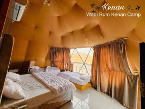a bedroom with two beds and a large window at Wadi Rum Kenan Camp in Wadi Rum