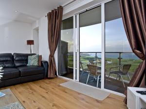 a living room with a couch and a balcony at Fistral View At Bredon Court in Newquay
