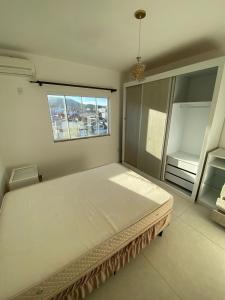uma cama grande em um quarto com janela em Apartamento de 2 quartos equipado em Imbituba sc em Imbituba