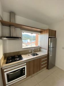 a kitchen with a stove and a sink and a refrigerator at Apartamento de 2 quartos equipado em Imbituba sc in Imbituba