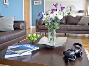 een salontafel met een vaas met bloemen en een camera bij The Penthouse Bay View in Westward Ho