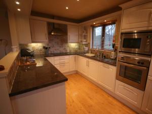 a kitchen with white cabinets and black counter tops at Woodpeckers Cabin in Bridlington