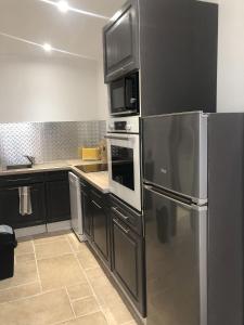 a kitchen with stainless steel appliances and black cabinets at Gîte atypique La Bastilac in Garganvillar