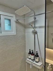 a shower with three bottles on a shelf in a bathroom at LIKE Mangwon in Seoul +47 photos