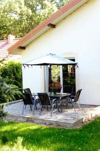 a table and chairs with an umbrella in front of a house at Dom wakacyjny Grabówka 18a in Milicz +7 photos