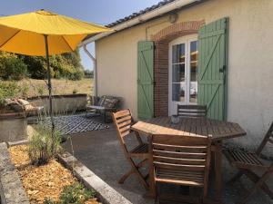 a patio with a table and chairs and an umbrella at Gîte atypique La Bastilac in Garganvillar