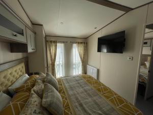 a small bedroom with a bed and a tv on the wall at Beaumont Elite in Skelmorlie +21 photos