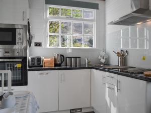 a white kitchen with white cabinets and a window at Field House Lodge in Borrowdale Valley +14 photos