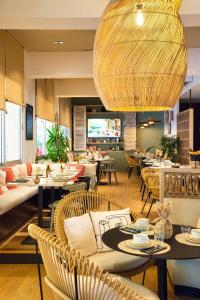 a restaurant with tables and chairs and a large chandelier at Hôtel BO & MIA in La Baule