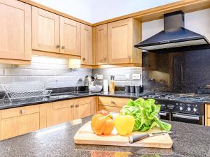 a kitchen with wooden cabinets and vegetables on a cutting board at Low Barn in Market Bosworth +15 photos