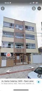 um prédio com um carro estacionado na frente em Apartamento de 2 quartos equipado em Imbituba sc em Imbituba