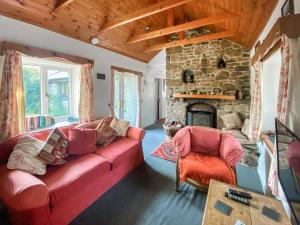 ein Wohnzimmer mit einem roten Sofa und einem Steinkamin in der Unterkunft Tor Barn in Lower Boscaswell