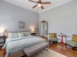 a bedroom with a bed with a ceiling fan and two chairs at Charm on Liberty in Savannah +16 photos
