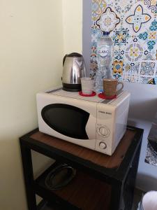 Un microondas sobre una mesa con dos tazas encima. en Cozy studio, en Seis de Octubre