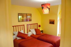 two beds in a room with yellow walls at A L'abri in Saint-Nolff