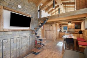 a living room and kitchen with a stone wall with a tv at Casa Promindoz in Valtournenche