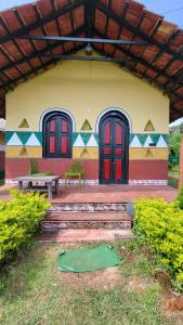 La Bella Hotels and Resorts في بوروليا: مبنى ذو أبواب حمراء ومقعد في المقدمة