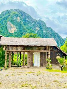 a wooden building with a mountain in the background at Dalasone Pool Villas with Stunning Mountain Views in Vang Vieng