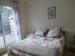 a bedroom with a bed with a quilt and a window at LA MONTILLE in Le Mont-Dore