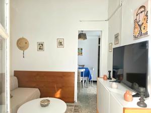 a living room with a couch and a tv at Les Sables Bleus in Le Kram