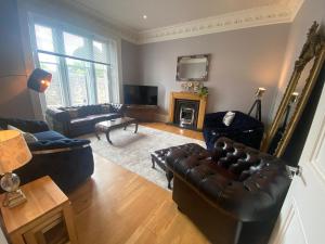 a living room with a leather couch and a television at Bruce on the Row-Historic Elegance near Edinburgh in Dunfermline
