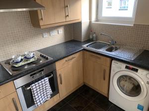 a kitchen with a washing machine and a sink at Stylish Apartment Sleeps 6, 2 Bed, 2 Bath, Free Parking & WIFI, Nr NEC & Uni in Coventry