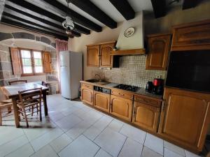 a kitchen with wooden cabinets and a table and a refrigerator at Le Logis d'Aliénor - Baie du Mont St-Michel in Baguer-Pican
