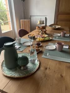 a wooden table with a green pot and plates of food at Gîte atypique La Bastilac in Garganvillar +9 photos