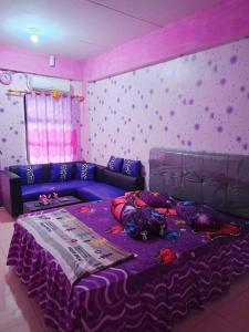 a bedroom with a purple bed and a purple couch at Penginapan Purple Syariah 