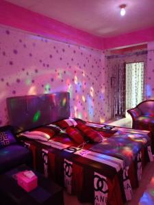 a bedroom with a bed and a purple wall with lights at Penginapan Purple Syariah 