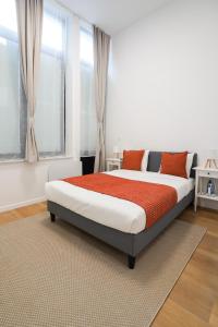una camera da letto con un letto con cuscini arancioni e una finestra di Appartment St guidon 1 a Bruxelles