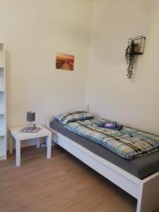 a bedroom with a bed and a nightstand with a table at Gemütliche Altbauwohnungen mit Einzelzimmern und Parkplatz direkt am Haus! in Bochum