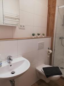 a white bathroom with a sink and a toilet at Gemütliche Erdgeschosswohnung mit 3 Einzelzimmern! in Niederdorla