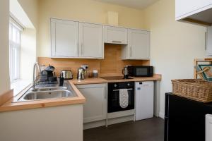 a kitchen with white cabinets and a sink at Historic Riverside House - Village, River Walks & Easy York Access in Cawood