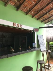 a bar with two stools and a sign on a wall at Camping Refugio SacodoCeu2026 in Saco do Ceu