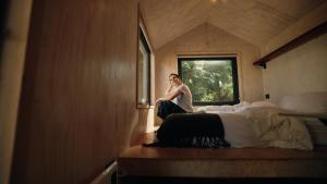 a man is sitting on a bed in a room at Cabins entre bosques y viñedos con vistas al valle - Tucu cabins in Maipo