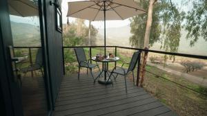 a table and chairs on a porch with an umbrella at Cabins entre bosques y viñedos con vistas al valle - Tucu cabins in Maipo +25 photos
