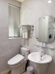 a white bathroom with a toilet and a sink at 星雨行館 Hotel in Mao-i-san-ts'un