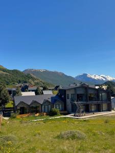 ein großes Haus mit Bergen im Hintergrund in der Unterkunft El Filo Aparts de Montaña in El Chalten