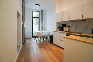 ブリュッセルにあるAppartment Wayez 3の白いキャビネットとテーブルと椅子のあるキッチン +5枚の写真