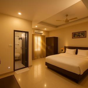 a bedroom with a large bed and a bathroom at The Royal Oak in Bhatkal