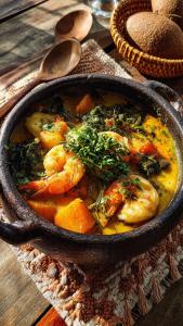 a pan of food with shrimp and vegetables on a table at CONFORTO IMBATIVEL - 25 metros do MAR - 2 Quartos com AR CONDICIONADOS SPLIT, Air Fryer, WI-FI, Disney Plus, Star Plus, HBO Max, Guarda Sol, Cadeiras de Praia e Caixa Térmica - 8 pessoas com Muito Conforto - Melhor Localização! in Guarapari