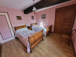 2 Betten in einem Schlafzimmer mit rosa Wänden und Holzböden in der Unterkunft La Maison Bienvenüe - Baie du Mont Saint Michel in Baguer-Pican