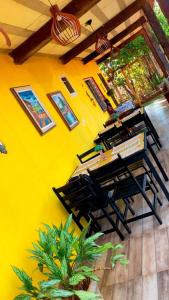 a room with a yellow wall with a table and chairs at Raizes do Cipó in Serra do Cipo