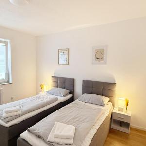 two beds in a room with white walls at Wohlfühl-Apartment mit großem Balkon, Netflix & Games in Barsinghausen