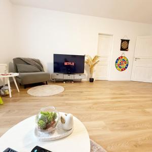 a living room with a table and a tv at Wohlfühl-Apartment mit großem Balkon, Netflix & Games in Barsinghausen