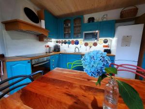 een blauwe keuken met een houten tafel en een vaas met een blauwe bloem bij TUTTO House in Frýdlant nad Ostravicí